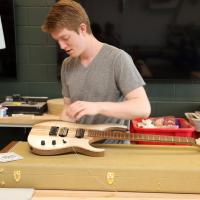 Gryphon Mawhorter, a rising senior in audio engineering technology, restrings his latest guitar in the "guitar lab" on Lambertus Hall's fourth floor.