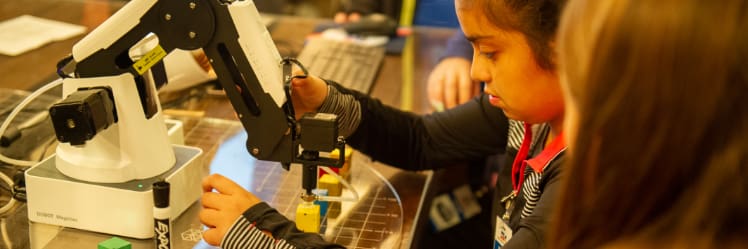 Elementary school students learn to execute tasks with a robotic arm much like those found in advanced manufacturing facilities.