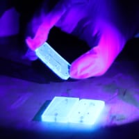 Close-up view of a microfluidic device, printed using Huachao Mao’s 3D printing innovation at Purdue’s Additive and Intelligent Manufacturing Lab, in ultraviolet light. (Purdue University photo/John O’Malley)