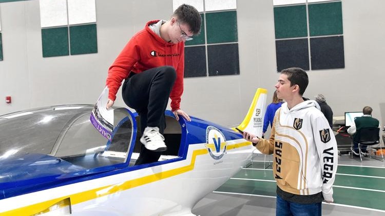 Pendleton Heights High School sophomore Jaxton Bush climbs out of an aircraft while Ian Chastain waits, taken at the school's aviation day event. (Photo Credit: Richard Sitler for The Herald Bulletin)