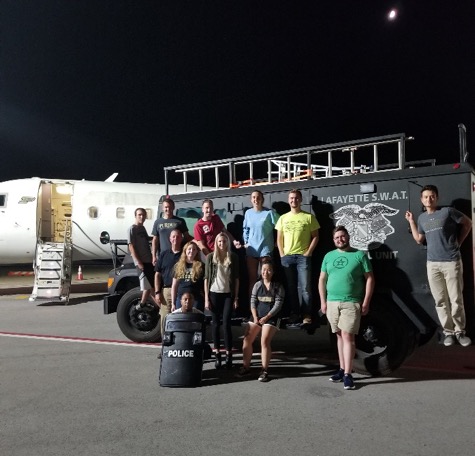 Students pose by a SWAT vehicle