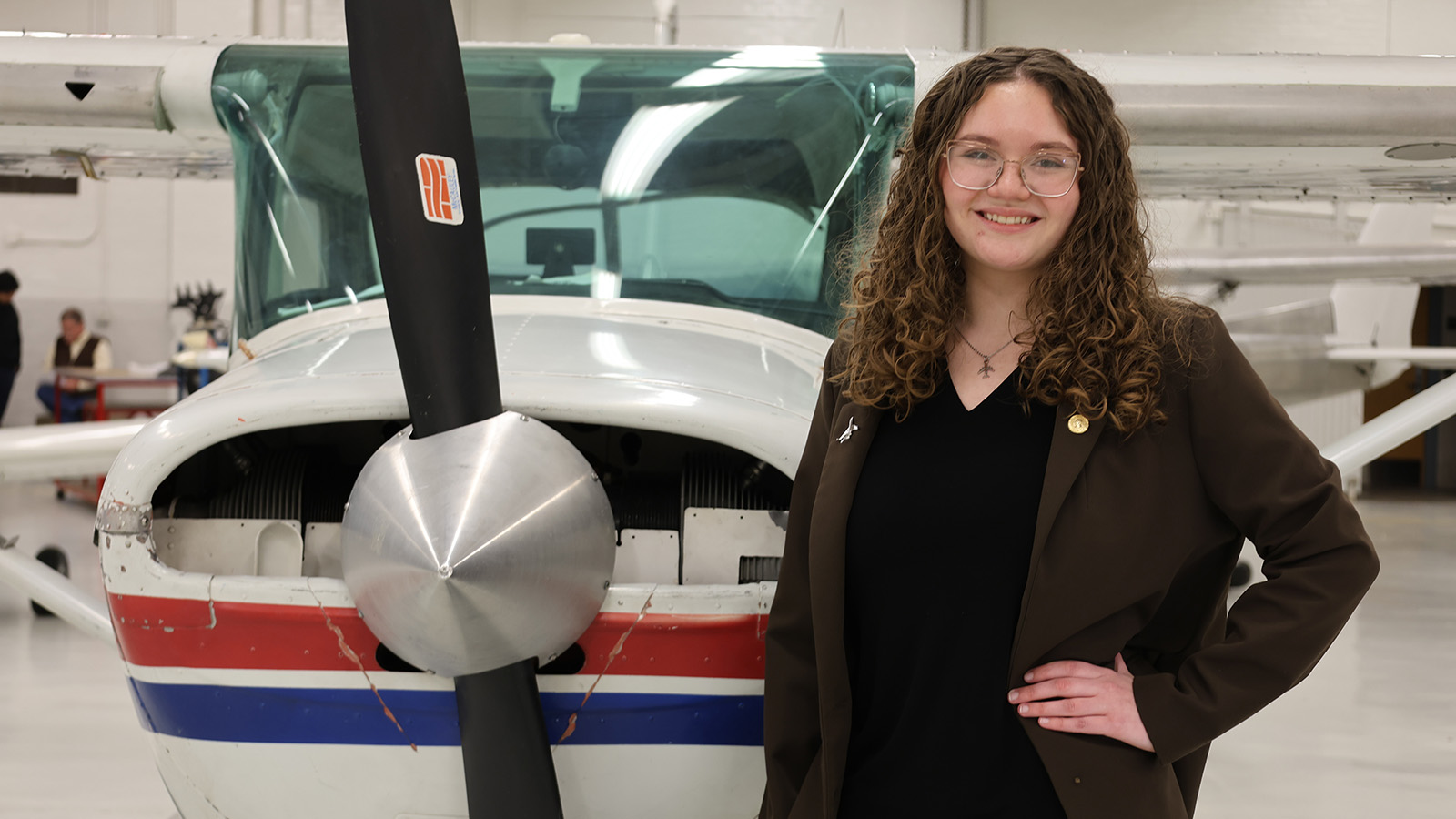 Purdue senior Allison Boyd stands next to a small plane in an aviation lab at the university airport.