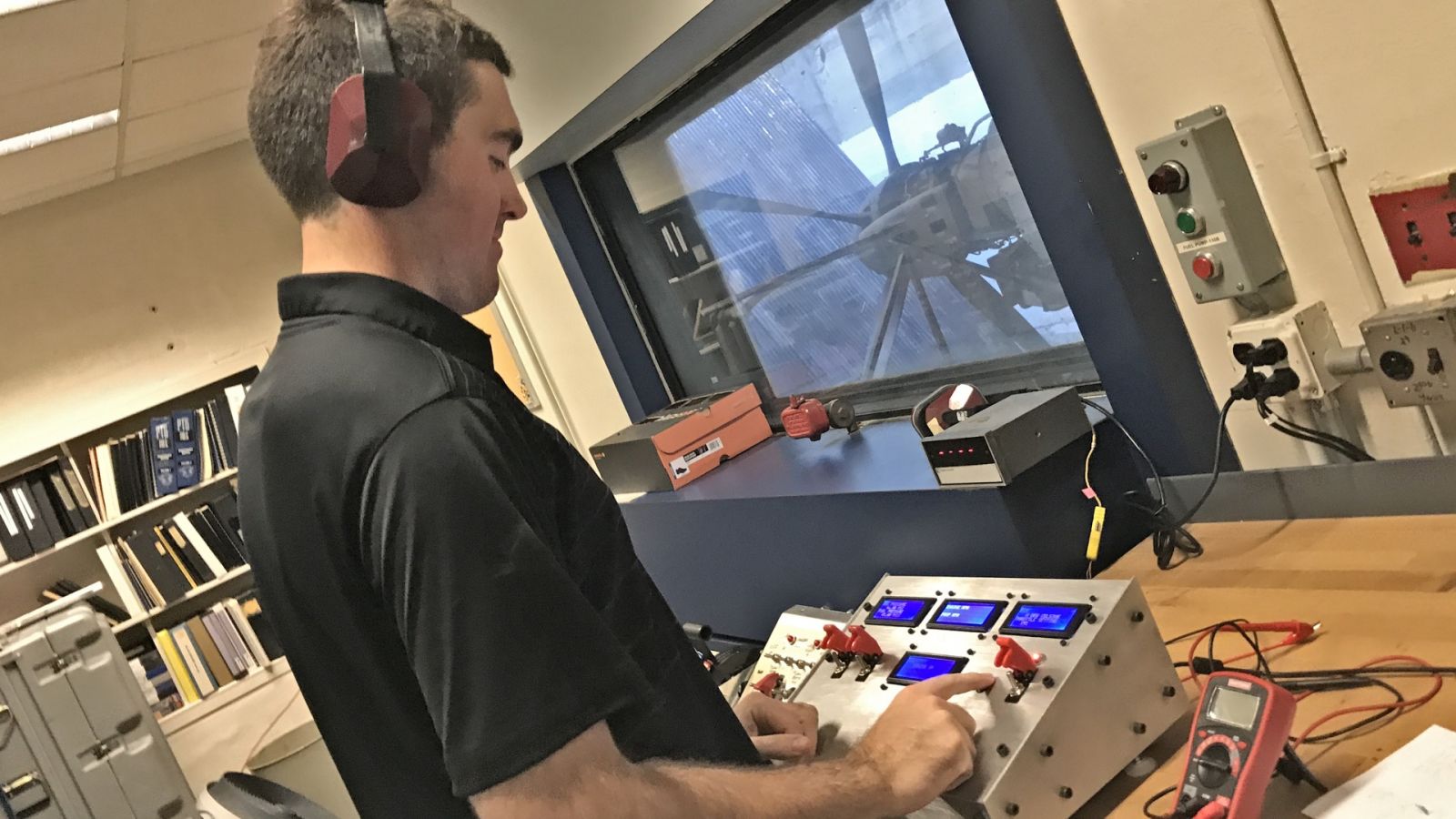 Brock Gillum prepares an engine test with his new portable microcontroller. The original prototype's shoebox is on the windowsill.