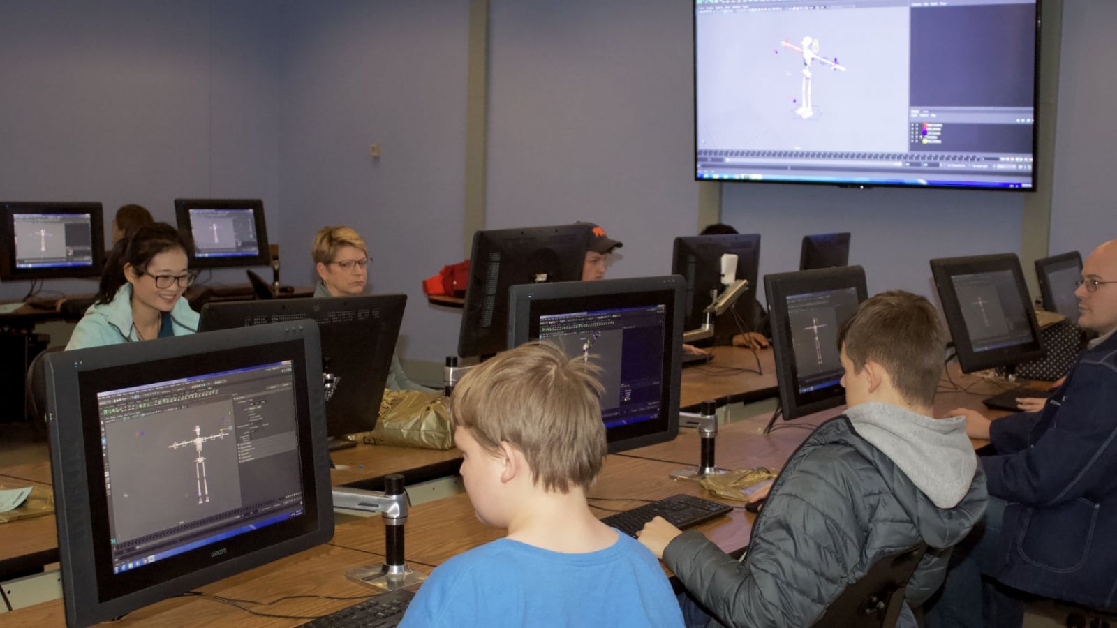 High school students & their parents posing a 3D character rig in a computer graphics technology workshop