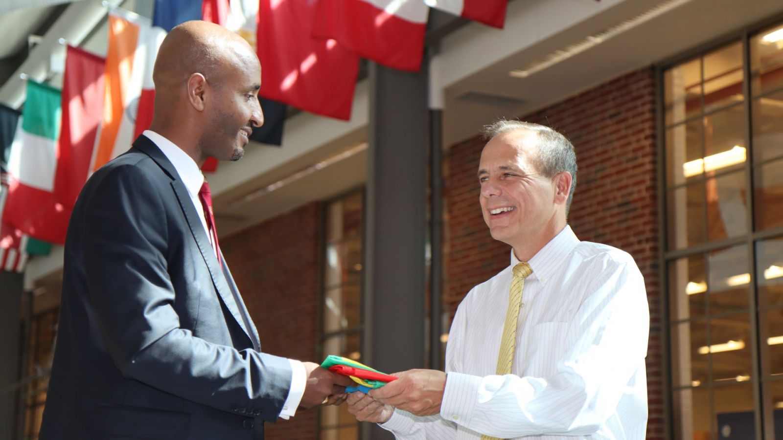 Dawit Lemma, founder and CEO of Krimson Aviation, presents the Ethiopian flag to Tom Frooninckx, interim head of Purdue’s School of Aviation and Transportation Technology, for Purdue’s Niswonger Aviation Technology Building to commemorate the scholarship announcement. (Purdue University photo/John O'Malley) (Download full-size photo in the Media Kit, below.)