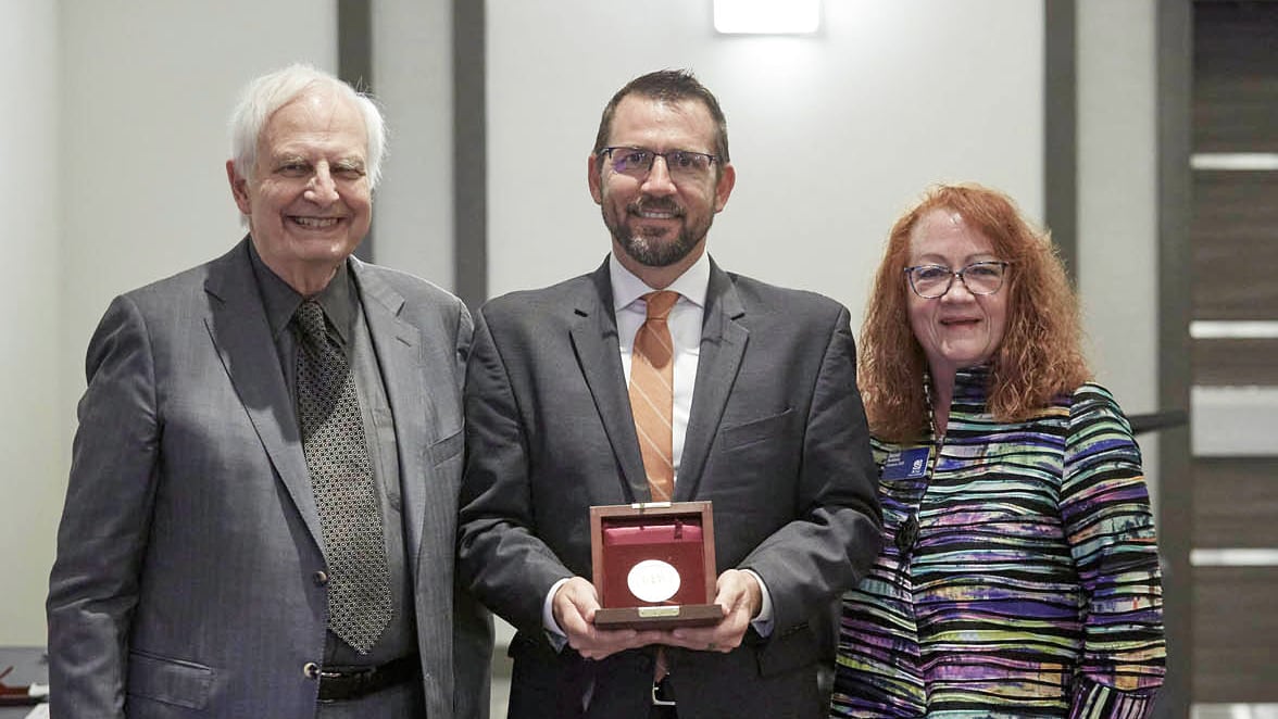 Chad Laux, center, accepts the Crosby Medal from chair A. Blanton Godfrey (left) and past chair Janet Raddatz (right) at the 2022 ASQ World Conference on Quality & Improvement in Anaheim, Calif. 