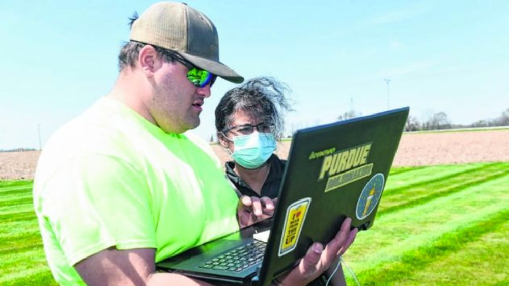Aaron McCambridge, left, a student at Purdue Polytechnic Anderson, works with Rashmi Deodeshmukh, assistant professor of practice, near a farm field lab on which the institute is partnering with NineStar Connect in Hancock County. (Submitted photo)