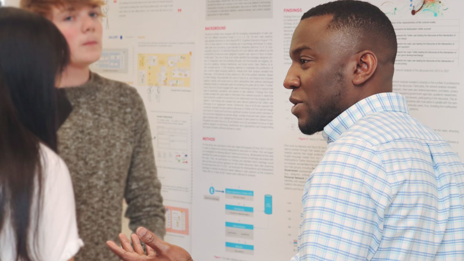 Ike Obi (right), graduate research assistant in the Department of Computer Graphics Technology, discusses research projects during a poster session at Stewart Center. (Purdue University photo/John O'Malley)