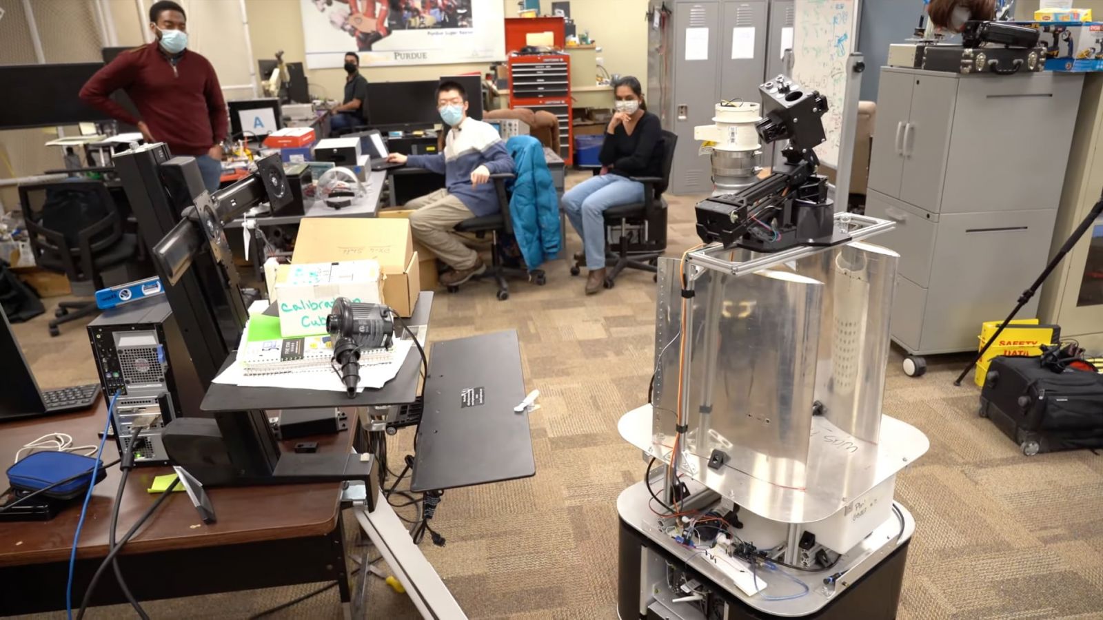 An interdisciplinary group of Purdue researchers, including Purdue Polytechnic's Haoguang Yang (center), test a robot designed to disinfect classrooms. (Image courtesy Purdue Mechanical Engineering)
