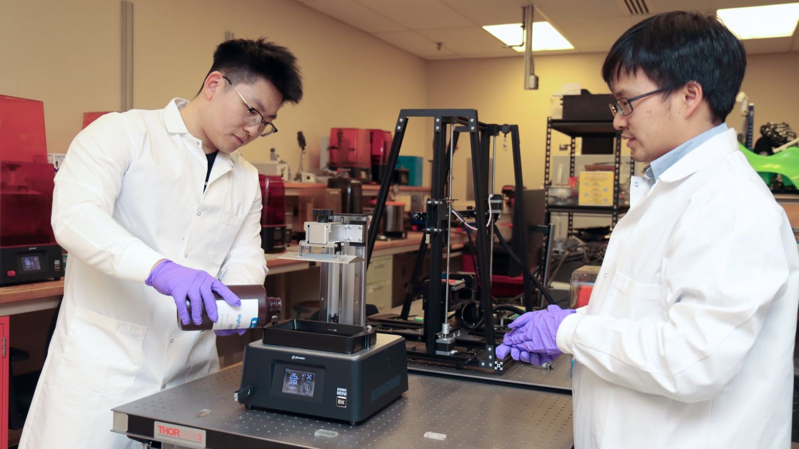 Yujie Shan, postdoctoral research assistant in Purdue’s School of Engineering Technology, and Huachao Mao, assistant professor of engineering technology, prepare a 3D printer to print samples of a microfluidic device. (Purdue University photo/John O’Malley)