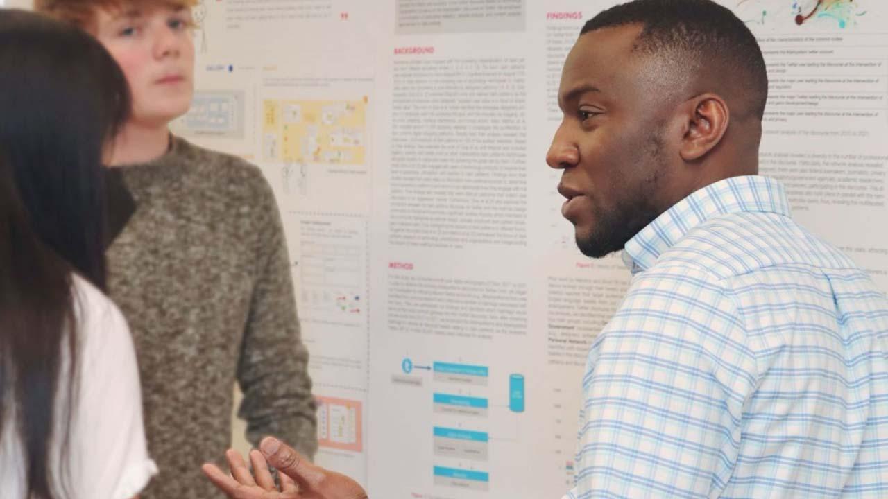 Ike Obi (right), PhD student in the Department of Computer and Information Technology, discusses research projects during a poster session at Stewart Center. (Purdue University photo/John O'Malley)